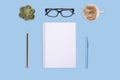 cup of coffee, notebook, pen, glasses and white empty sheet on blue background. Flat Lay with no people. View from the top. Royalty Free Stock Photo