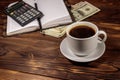 Cup of coffee and notepad with dollars, pencil and calculator on wooden desk. Financial concept Royalty Free Stock Photo