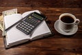 Cup of coffee and notepad with dollars, pencil and calculator on wooden desk. Financial concept Royalty Free Stock Photo