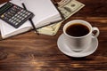 Cup of coffee and notepad with dollars, pencil and calculator on wooden desk. Financial concept Royalty Free Stock Photo