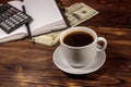 Cup of coffee and notepad with dollars, pencil and calculator on wooden desk. Financial concept Royalty Free Stock Photo