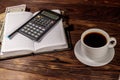 Cup of coffee and notepad with dollars, pencil and calculator on wooden desk. Financial concept Royalty Free Stock Photo