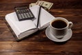 Cup of coffee and notepad with dollars, pencil and calculator on wooden desk. Financial concept Royalty Free Stock Photo