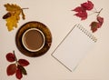 Cup of coffee, notepad, oak leaves, acorns, red maple leaves on a beige background.