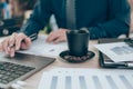 Cup of coffee on office desk and Accountant working on calculator to calculate company data, document and report on desk office.