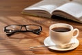 Cup of coffee, open book and glasses on a desk. Royalty Free Stock Photo