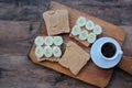 Cup of coffee and peanut butter banana toasts on wooden background. Slices of whole wheat bran bread with peanut paste on cutboard Royalty Free Stock Photo