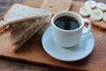 Cup of coffee and peanut butter banana toasts on wooden background. Slices of whole wheat bran bread with peanut paste on cutboard Royalty Free Stock Photo