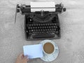 A cup of coffee, person holding blank note paper and old typewriter vintage on background. Royalty Free Stock Photo