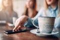 Cup of coffee and phone on wooden table, closeup