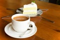 Cup of coffee with piece of cake on wooden table in cafe. Royalty Free Stock Photo