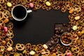 Cup of coffee among pile of various cookies, almonds and multicolored caramelon,black chocolate with nuts, black wooden background