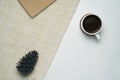Cup of coffee and pine cone on brown yarn background. Flat lay top view.
