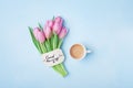 Cup of coffee, pink tulip flowers and note good morning on blue table top view. Beautiful breakfast on Mothers or Womans day. Royalty Free Stock Photo