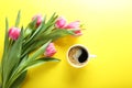 Cup of coffee and pink tulips on yellow background, top view Royalty Free Stock Photo