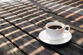 A cup of coffee placed on a wooden floor  With the natural light of the sun crossing Royalty Free Stock Photo