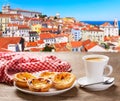 cup of coffee and plate of portuguese pastries - Pastel de nata over Alfama district lisbon Portugal