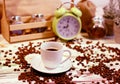 A cup of coffee on a platter with lots of sprinkled coffee beans. Alarm clock arrows at 9 am. Wooden textured table