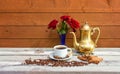 Cup of coffee, coffee pot, coffee beans, red roses and spices on aged wooden table Royalty Free Stock Photo