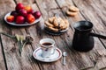 Cup of coffee and pot with tasty snacks on wood