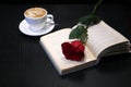 Cup of coffee, a red rose and a book on the table Royalty Free Stock Photo