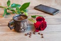 A cup of coffee, a red rose and a smartphone on a wooden table Royalty Free Stock Photo