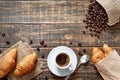 Cup of coffee, roasted beans, croissants on a wooden background Royalty Free Stock Photo