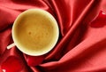 Cup of coffee and rose petals on folded red silk