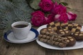 Cup of coffee, roses and plate with different cookies on a table