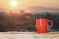 A cup of coffee on a rustic table against the morning rising sun