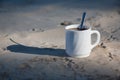 A cup of coffee on the sand. Bird footprints in the sand and a cup of white coffee with black coffee in the light of dawn. Royalty Free Stock Photo