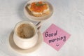 a cup of coffee with a sandwich with red caviar and next to a note with the words good morning. top view. Royalty Free Stock Photo