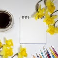 Cup of coffee and a saucer, daffodils and pencils on a white background Royalty Free Stock Photo