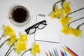 Cup of coffee and a saucer, daffodils and pencils on a white background Royalty Free Stock Photo