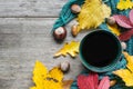 Cup of coffee, scarf and autumn leaves on vintage wood background