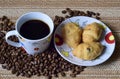 A Cup of coffee is on the scattered coffee beans, next saucer with croissants. Royalty Free Stock Photo