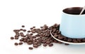 A cup of coffee and scattered coffee beans on white background