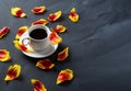 A Cup of coffee and scattered Tulip petals on the stone table