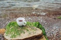 Cup of coffee on the sea water and stone background. Sea freshness morning concept