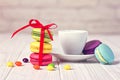 Cup of coffee with set of milticolored macarons and sweets on white wood and bricks background