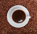 Cup of coffee sitting in a bed of coffee beans Royalty Free Stock Photo
