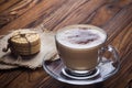 A cup of coffee and small cookies on an antique wooden table