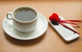 Cup of coffee, the smartphone with red heart on a wooden table Royalty Free Stock Photo
