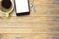 Cup of coffee,smartphone and white earphone on wood table in work place. Royalty Free Stock Photo