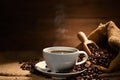 Cup of coffee with smoke and coffee beans on burlap sack on old wooden background Royalty Free Stock Photo