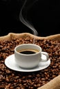 Cup of coffee and smoke on toasted coffe grains