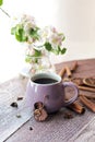 Cup of coffee, spices, apple flowers on a wooden windowsill