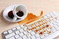Cup of coffee spilled over computer keyboard on wooden table Royalty Free Stock Photo