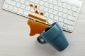 Cup of coffee spilled over computer keyboard on white wooden table, flat lay Royalty Free Stock Photo