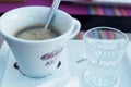 A cup of coffee and a spoon in it with a glass of cold water Royalty Free Stock Photo